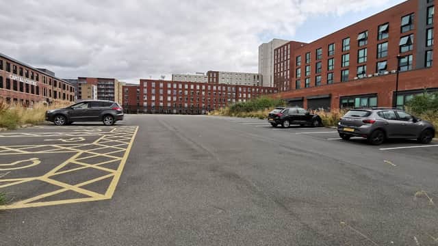 Milton Street Car Park with empty spaces, surrounded by modern brick buildings under a cloudy sky.