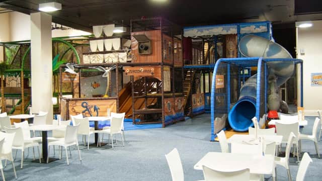 Indoor play area with climbing structures, slides, and seating for diners in a spacious, colorful environment.