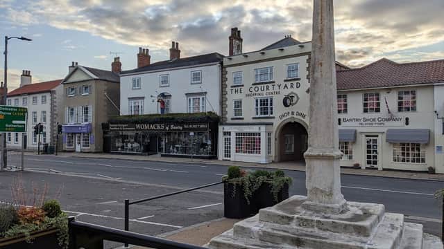 Pay & Display car park with shops, a monument, and buildings under a cloudy sky in Bawtry, Yorkshire.