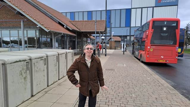 Monks Cross Park and Ride with a man in a brown coat, a red bus, and a Cineworld building in the background.