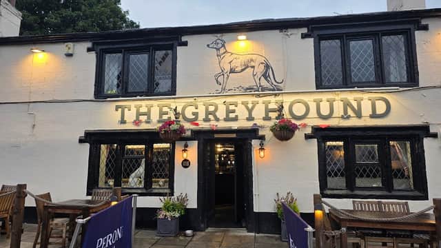 Historic restaurant with a greyhound logo, outdoor seating, and flower planters in Tong, Yorkshire.