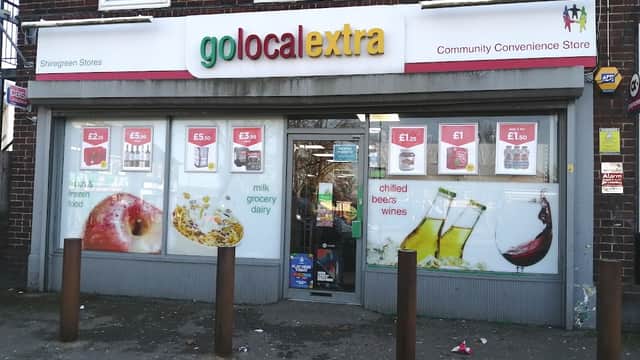 Brightly colored storefront with "Go Local Extra" sign, displaying groceries, drinks, and promotional prices on windows.