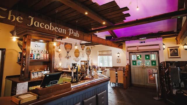 Cozy interior of The Jacobean Pub, featuring a wooden bar, colorful decor, and soft lighting.
