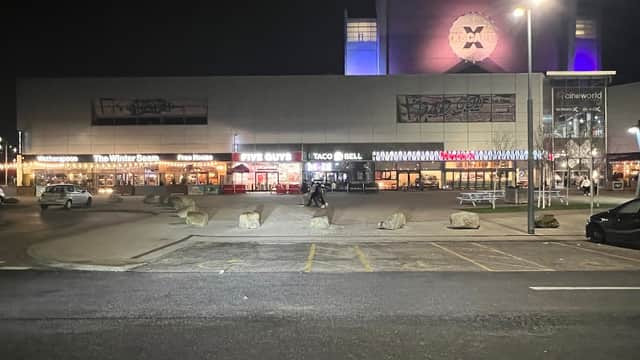 Xscape Castleford car park at night, featuring restaurants like Five Guys and Taco Bell, with bright signage and lights.