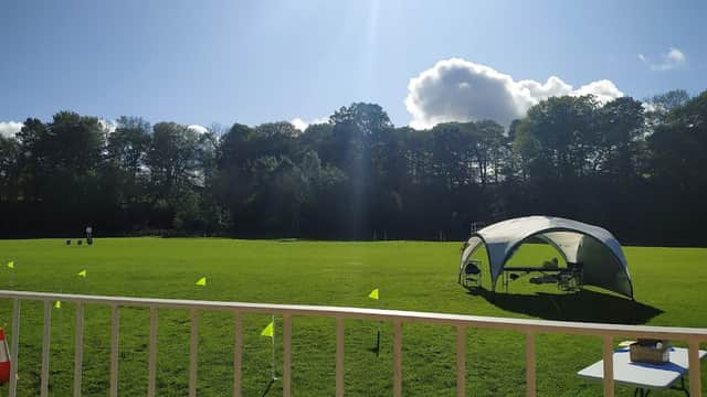 Bright sunny day at Lonsdale Sports Pavilion, featuring a green field, a tent, and flags marking the area.