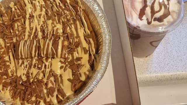 Decadent dessert with chocolate drizzle and sprinkles alongside a creamy drink topped with whipped cream and chocolate.