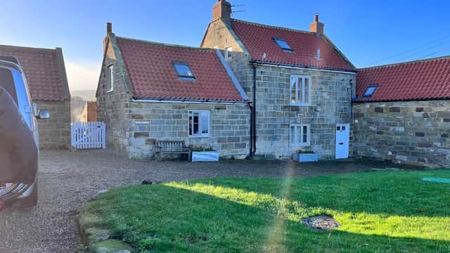 Stone building with red roof, grassy area, and clear blue sky in Kettleness, Yorkshire.