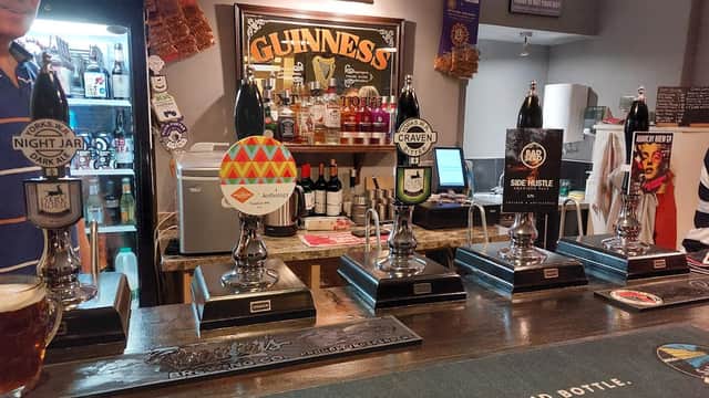 Bar interior featuring five beer taps, a selection of bottles, and a sign for Gallagher's Ale House.