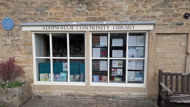 Addingham Community Library's stone exterior features large windows displaying books and community notices.