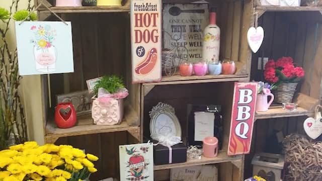 Colorful floral arrangements and decorative signs displayed on wooden crates, showcasing a charming floral shop atmosphere.