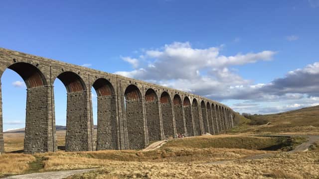 Historic stone viaduct with multiple arches, set against a blue sky and grassy landscape in Gearstones, Yorkshire.