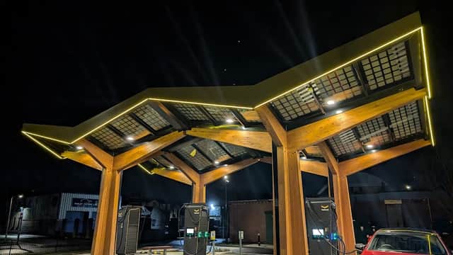 Fastned Charging Station features a modern wooden structure with illuminated charging points and a parked electric car.