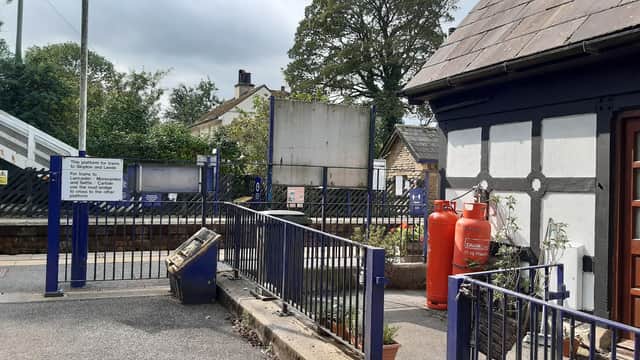 A quaint station building with blue and white accents, surrounded by greenery and a sign indicating Gargrave station.