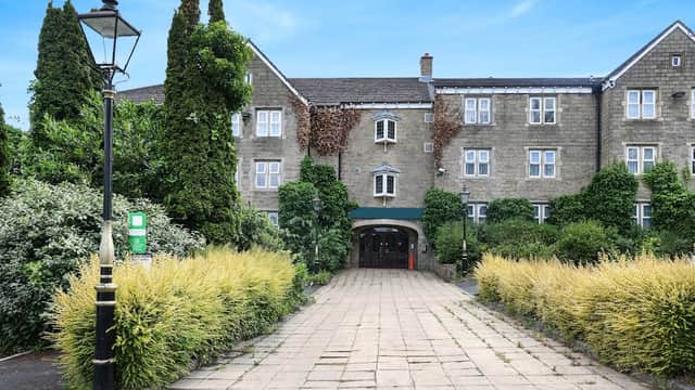 OYO Tong Park Hotel features a stone facade, lush greenery, and a cobblestone path leading to the entrance.