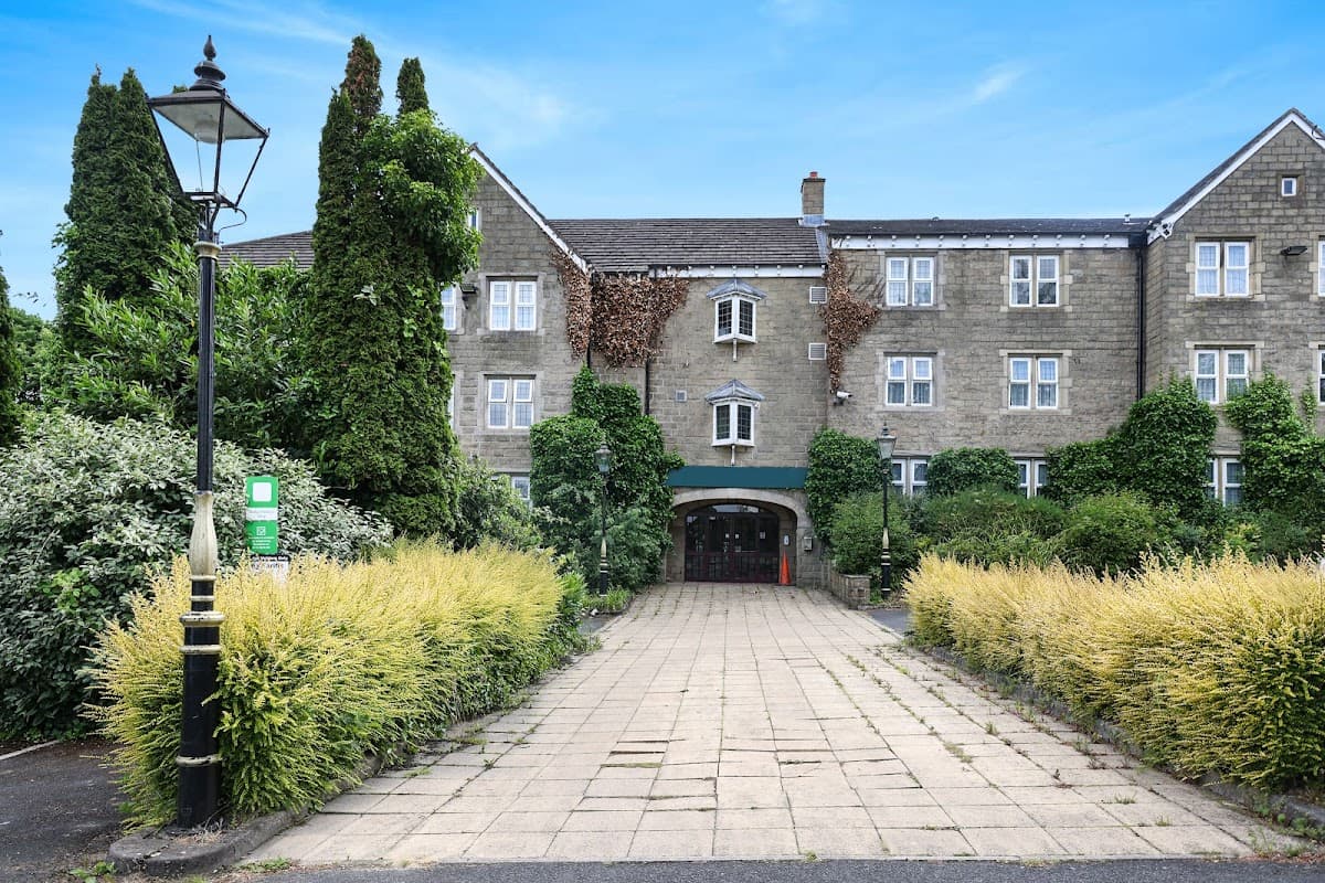 OYO Tong Park Hotel features a stone facade, lush greenery, and a cobblestone path leading to the entrance.