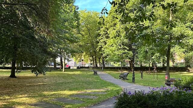 Pathway winding through lush greenery and flowering plants in Churchfields Peace Gardens, Barnsley.