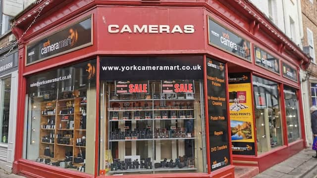 Red storefront of York Camera Mart featuring cameras, accessories, and a sale sign, located in York, Yorkshire.