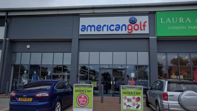 American Golf store front with signage, two parked cars, and promotional displays for Father's Day gifts.