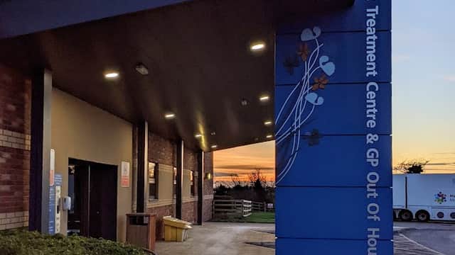 Beverley Urgent Treatment Centre entrance with a blue sign, modern architecture, and a sunset in the background.