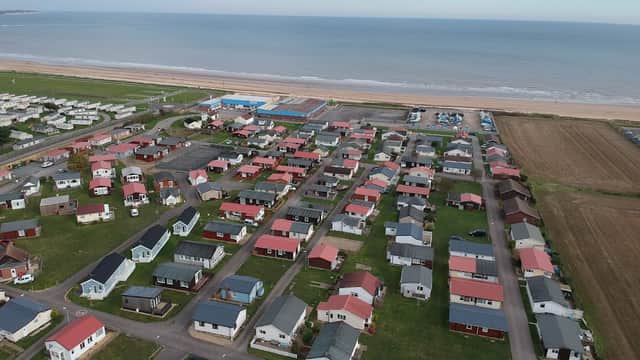 Aerial view of South Shore Holiday Village, featuring colorful chalets near the beach and a vast sea in the background.