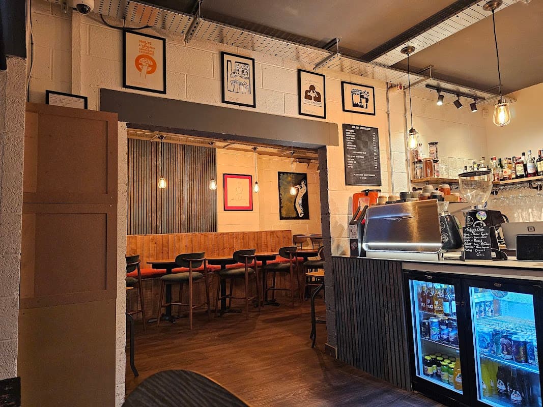 Cozy interior of Bottle and Bean with bar, seating, framed art, and illuminated shelves showcasing drinks.