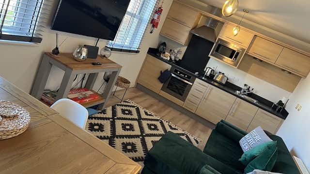 Modern kitchen and cozy living area with green sofa, TV, dining table, and decorative rug in Bay Retreat, Filey.