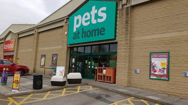 Entrance to Pets at Home shop with green signage, outdoor seating, and promotional posters in Halifax, Yorkshire.