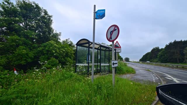 Bus stop shelter beside a road, with directional signs and lush greenery in Whitwell Hill, Yorkshire.