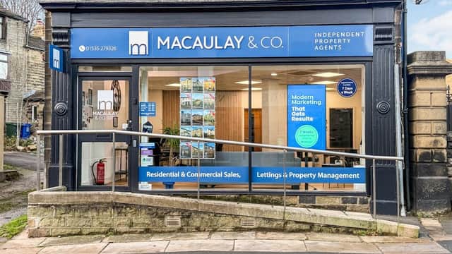 Macaulay & Co. storefront in Cross Hills, featuring a blue sign, large windows, and promotional posters inside.
