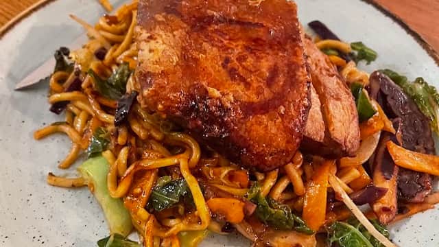 A plate of crispy pork on stir-fried noodles with vegetables, served at Black Swan bar in Eastrington, Yorkshire.