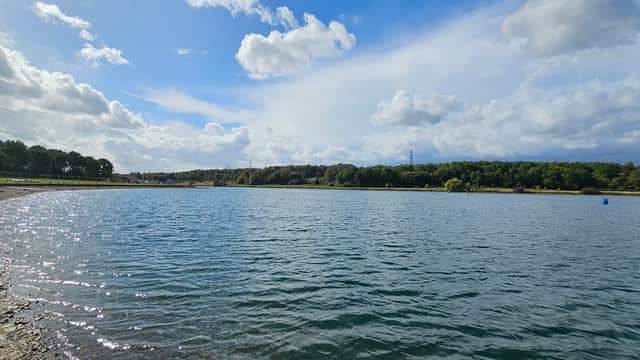 Serene lake with shimmering water, surrounded by trees and a clear sky, near the Rother Valley Watersports Centre.