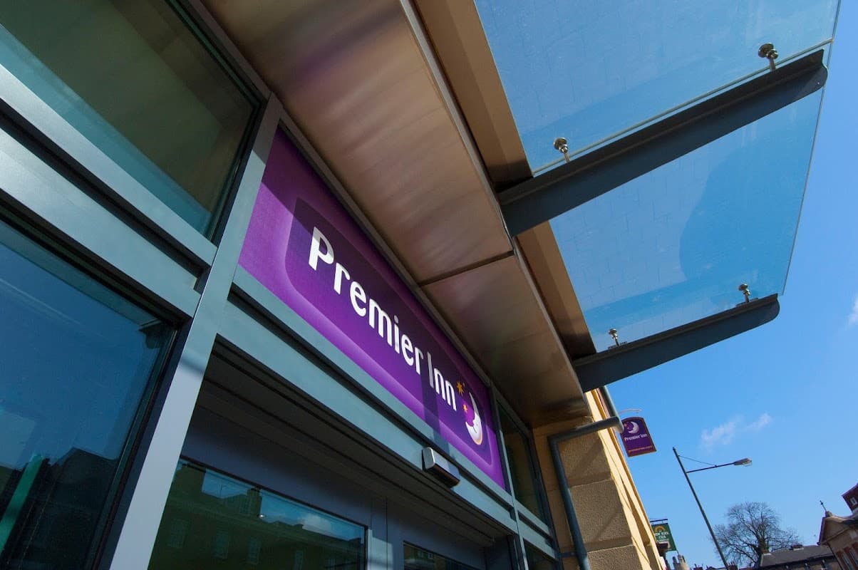 Premier Inn hotel entrance with a purple sign, glass awning, and clear blue sky in York, Yorkshire.