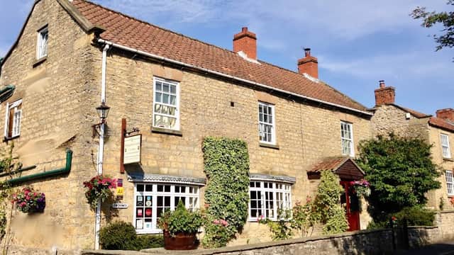 Charming stone building with a red-tiled roof, surrounded by greenery and colorful flower pots in Beadlam, Yorkshire.
