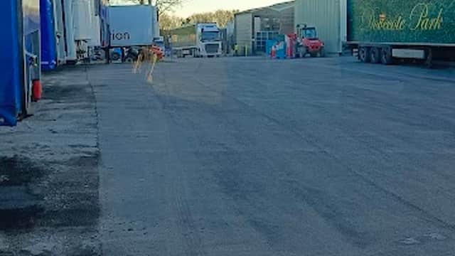 Car park with multiple storage containers and vehicles, set against a clear sky in Cridling Stubbs, Yorkshire.