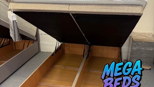 A stylish bed frame with a lifted mattress revealing storage space underneath, showcased in a shop setting.