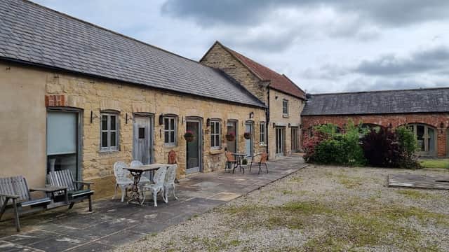 Stone cottage with outdoor seating, planters, and a gravel courtyard under a cloudy sky in Barton-le-Street, Yorkshire.