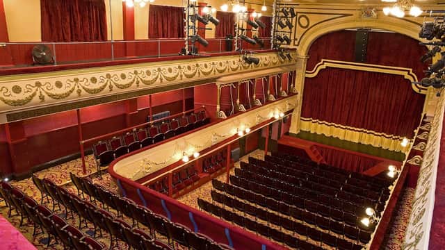 Interior of City Varieties Music Hall featuring red velvet seats, ornate decor, and a stage with golden accents.