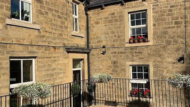 Stone cottage with flower boxes, a small patio area, and a clear blue sky in Bewerley, Yorkshire.
