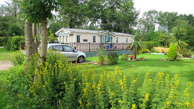 A caravan surrounded by lush greenery and vibrant yellow flowers at Thirkleby Hall Caravan Park in Yorkshire.