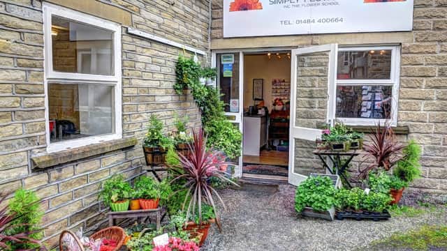 Charming flower shop entrance with potted plants, vibrant flowers, and a welcoming open door in Brighouse, Yorkshire.