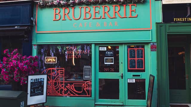 Brightly colored café facade with "Bruberrie Café & Bar" sign, outdoor seating, and floral decorations.
