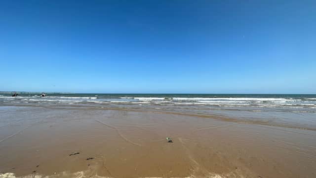 Sandy beach with gentle waves under a clear blue sky at East Yorkshire Coast AONB, Wilsthorpe.
