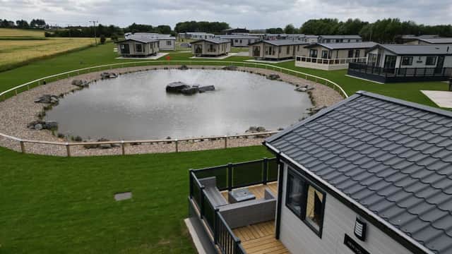 Hornsea Leisure Park features modern lodges around a landscaped pond with a central rock, set in a green, open area.