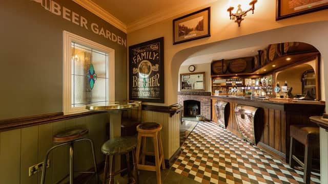 Cozy bar interior with wooden accents, checkered floor, and a stained glass window, featuring a welcoming atmosphere.