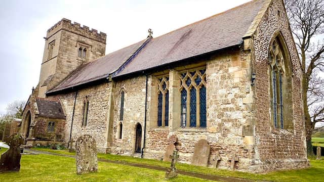 Historic stone church with a tall tower, arched windows, and a grassy cemetery in Nunburnholme, Yorkshire.