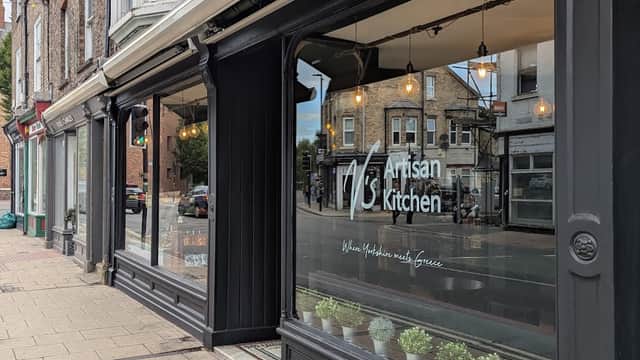 V's Artisan Kitchen storefront with large windows, hanging lights, and potted plants along the sidewalk in York.