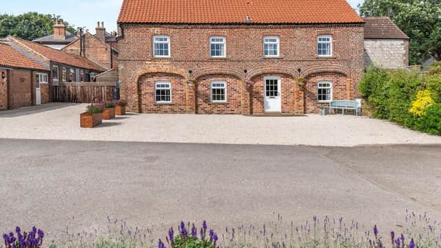 Brick farmhouse with a red-tiled roof, surrounded by gravel, planters, and a flower bed in Willerby, North Yorkshire.