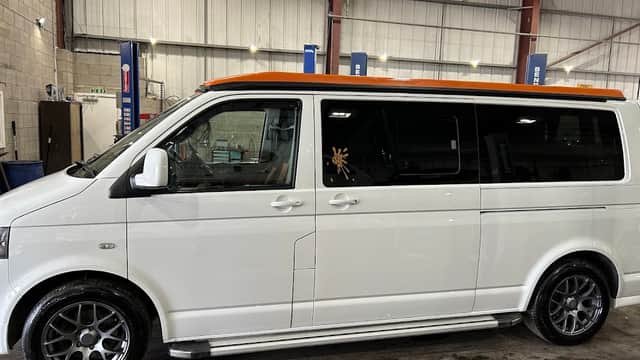 White van with an orange roof, sleek wheels, parked inside a spacious workshop with tools and equipment visible.