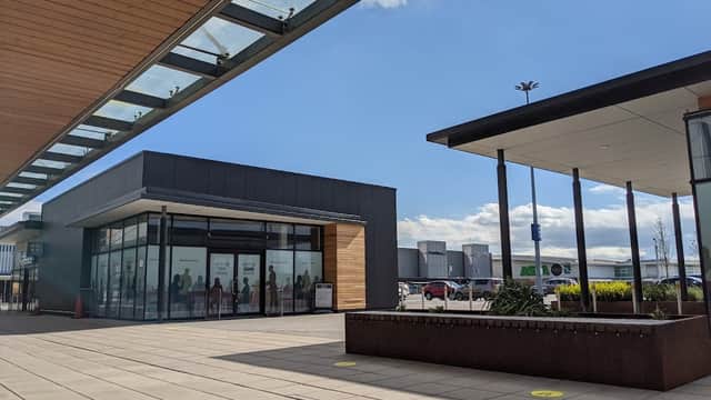 Modern shopping park with glass faΓ§ade, outdoor seating, and clear blue sky in Earswick, Yorkshire.
