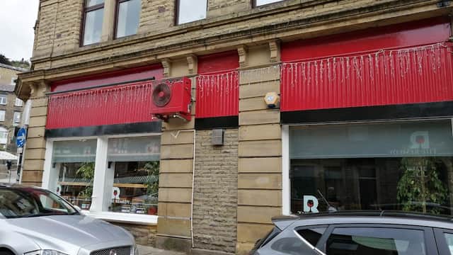 Red and stone faΓ§ade of The Remedy Wine Merchants shop, featuring large windows and decorative elements.